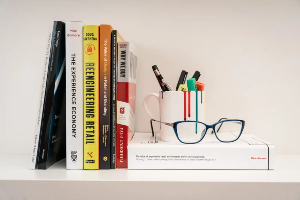 Elisa's book and thesis on a shelf with her glasses, her mug and pens